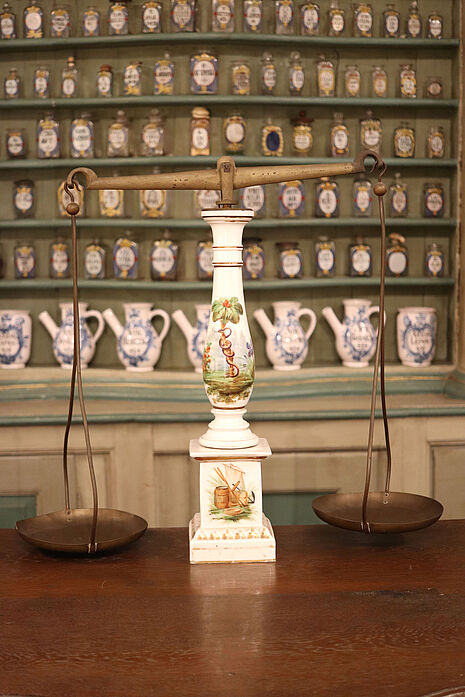 Abbildung 1: Aufstellung der Standwaage auf dem Rezepturtisch der Offizin der Klosterapotheke des Benediktinerklosters zu Schwarzach im Deutschen Apotheken-Museum (Inv.-Nr. VI A 35, © Dt. Apotheken Museum-Stiftung)